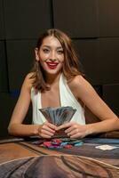 contento giovane donna vincente nel poker, seduta wth banconote a tavolo nel casinò foto