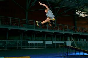 pattinatore saltare alto a partire dal grande aria rampa l'esecuzione trucco. in casa pattinare parco attrezzatura. foto