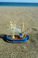 giocattolo pesca barca su il spiaggia foto