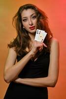 brunetta ragazza con orecchino nel naso, nel nero vestire. mostrando Due assi, in posa su colorato sfondo. gioco d'azzardo, poker, casinò. avvicinamento foto