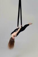 bellissimo ragazza nel un' nero sport completo da uomo è l'esecuzione un acrobatico elementi nel un' studio. foto