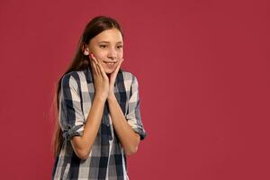 bellissimo adolescenziale ragazza nel un' casuale scacchi camicia è in posa contro un' rosa studio sfondo. foto