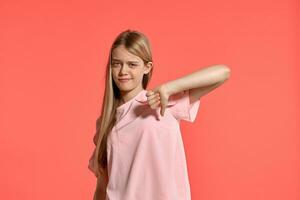 studio ritratto di un' bellissimo ragazza bionda adolescente nel un' roseo maglietta in posa su rosa sfondo. foto
