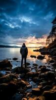 ai generato un' uomo in piedi su un' roccia guardare a il tramonto nel il lago. foto