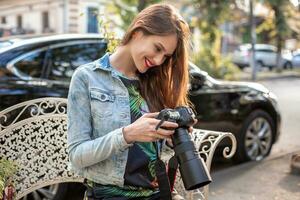 ritratto di professionale femmina fotografo su il strada Fotografare su un' telecamera. foto