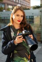 attraente turista donna fotografo con telecamera, all'aperto nel città strada. foto