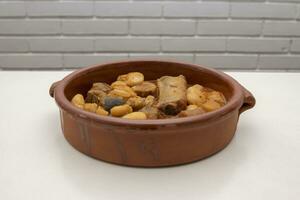 un' terracotta piatto con asturiano fabada, un' tipico spagnolo fagiolo stufato, su un' bianca sfondo. spagnolo cibo concetto. foto