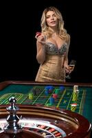 giovane bionda donna indossare bellissimo sexy brillante vestito è giocando roulette nel il casinò foto