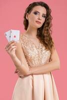 giovane bellissimo donna Tenere il vincente combinazione di poker carte su rosa sfondo. Due assi foto