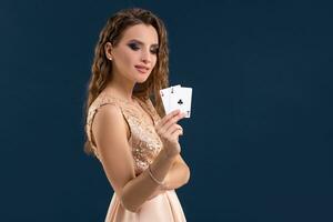 giovane bellissimo donna Tenere il vincente combinazione di poker carte su buio blu sfondo. Due assi foto