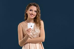 giovane bellissimo donna Tenere il vincente combinazione di poker carte su buio blu sfondo. Due assi foto