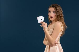 giovane bellissimo donna Tenere il vincente combinazione di poker carte su buio blu sfondo. Due assi foto