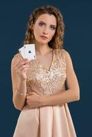giovane bellissimo donna Tenere il vincente combinazione di poker carte su buio blu sfondo. Due assi foto