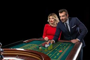 bellissimo e bene vestito coppia giocando roulette nel il casinò foto