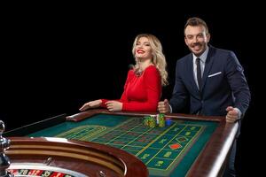 bellissimo e bene vestito coppia giocando roulette nel il casinò foto