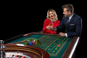 bellissimo e bene vestito coppia giocando roulette nel il casinò foto