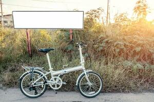 bicicletta pieghevole parcheggiata su prato con bianca manifesto foto