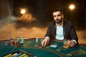 un' giovane uomo nel un' attività commerciale completo da uomo seduta a il poker tavolo. uomo scommesse. il giocatore a il gioco tavolo giocando carte. foto