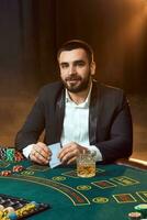 un' giovane uomo nel un' attività commerciale completo da uomo seduta a il poker tavolo. uomo scommesse. il giocatore a il gioco tavolo giocando carte. foto