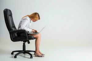 giovane donna seduta su il sedia e utilizzando il computer portatile foto