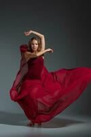 giovane bellissimo ballerino nel rosso vestito in posa su un' buio grigio studio sfondo foto