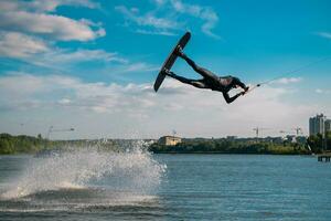 professionale wakeboarder l'esecuzione saltare al di sopra di acqua mentre Tenere su trainare corda foto