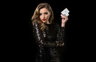 giovane donna Tenere giocando carte contro un' nero sfondo foto