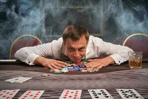 bello emotivo uomo è giocando poker seduta a il tavolo nel casinò. foto