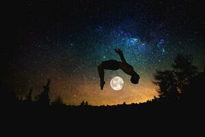 sportivo uomo salto silhouette a il notte stellato cielo e Luna sfondo. foto