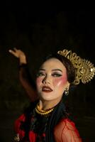 un asiatico donna con trucco su sua viso e indossare un' nero scialle mentre danza foto