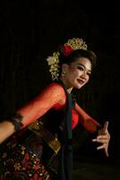 vicino su di un indonesiano donna nel un' balinese ballerino costume in posa molto meravigliosamente a notte foto