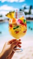 ai generato mano Tenere un' colorato cocktail bicchiere con un' tropicale spiaggia sfondo foto