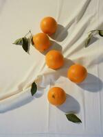 ai generato otto mandarini su bianca stoffa, con verde foglie, ogni giorno effimero, biologico Materiale foto