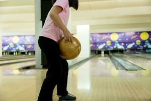 giovane ragazza avendo divertimento con palla nel bowling club. foto