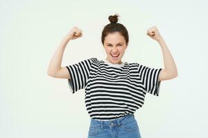 Immagine di impertinente, forte e fiducioso donna Spettacoli sua muscoli, flessione bicipite, raccolta sua braccia alto, in piedi al di sopra di bianca sfondo foto