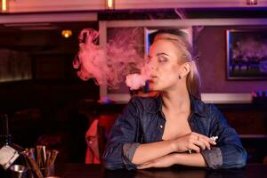 giovane bella donna Fumo un elettronico sigaretta a il Vape bar foto