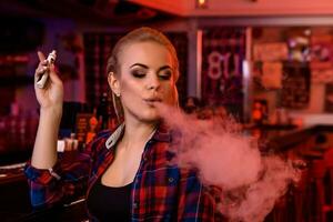 giovane bella donna Fumo un elettronico sigaretta a il Vape bar foto