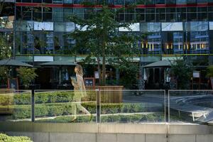 silhouette di giovane attività commerciale donna nel beige completo da uomo, a piedi nel città centro, in posa vicino ufficio edifici, andando per opera foto