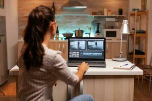 indietro Visualizza di creativo regista Lavorando su un' film su il computer portatile durante mezzanotte. soddisfare Creatore nel casa Lavorando su montaggio di film utilizzando moderno Software per la modifica in ritardo a notte. foto