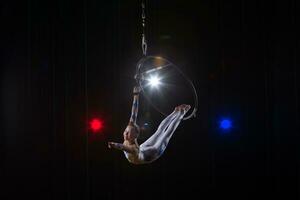 esegue un' circo ragazza attrice. circo aereo ginnasta su il cerchio. acrobazie. adolescente esegue un acrobatico trucco nel il aria foto