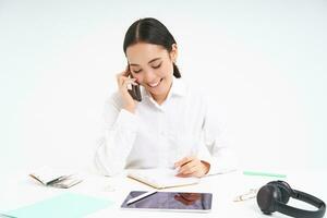 Immagine di asiatico donna nel ufficio, parla su cellulare, discutere opera con cliente su mobile Telefono, bianca sfondo foto