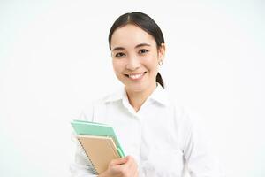 asiatico donna, insegnante con i Quaderni, sorridente e guardare fiducioso, isolato su bianca sfondo foto