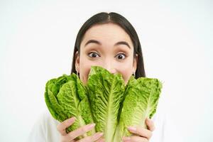 ritratto di carino giovane donna Spettacoli sua viso con cavolo, piace la verdura, mangia salutare nutriente dieta cibo, detiene lattuga, bianca sfondo foto