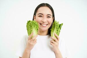 salutare dieta e biologico cibo. sorridente asiatico donna mostrando cavolo, mangiare lattuga, detergente sua corpo, su disintossicazione, bianca sfondo foto