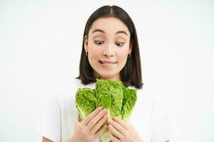 contento donna vegetariano sembra a delizioso lattuga, piace mangiare fresco cabina, vegano cibo, bianca sfondo foto