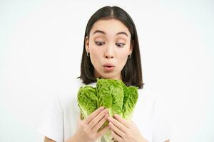 contento donna vegetariano sembra a delizioso lattuga, piace mangiare fresco cabina, vegano cibo, bianca sfondo foto