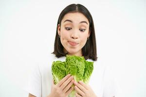 contento donna vegetariano sembra a delizioso lattuga, piace mangiare fresco cabina, vegano cibo, bianca sfondo foto