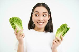 salutare dieta e biologico cibo. sorridente asiatico donna mostrando cavolo, mangiare lattuga, detergente sua corpo, su disintossicazione, bianca sfondo foto