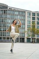 verticale tiro di danza ragazza nel cuffia, ascoltando musica su strada, godendo suono nel auricolari foto