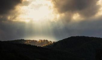 un buco nel cielo - il sole illumina la cima della montagna foto